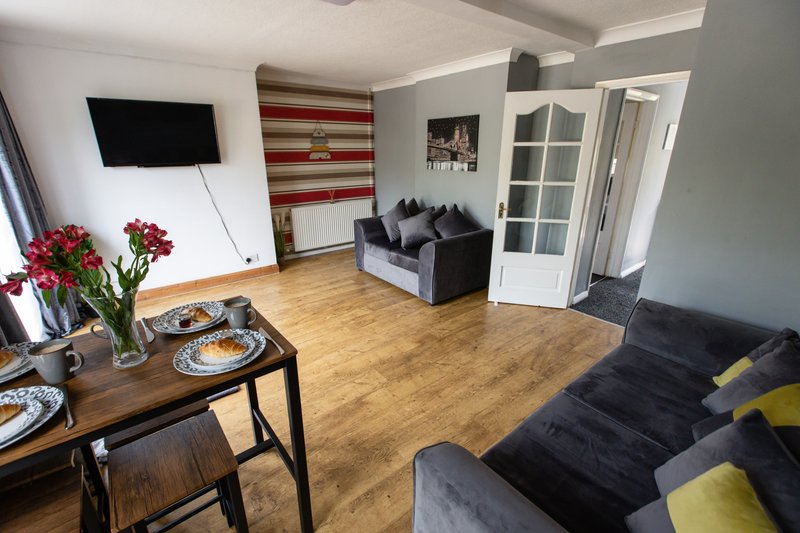 Open-plan living room with dining table, sofas, TV, wooden flooring and striped accent wall