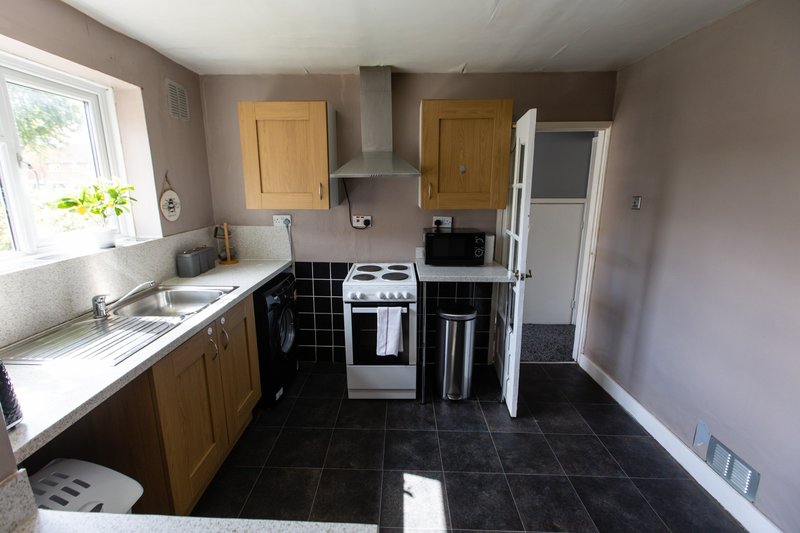 Kitchen with wooden cabinets, white countertops, black tiled floor and white appliances