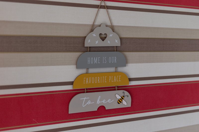 Decorative wall hanging with stacked wooden signs displaying home-themed phrases
