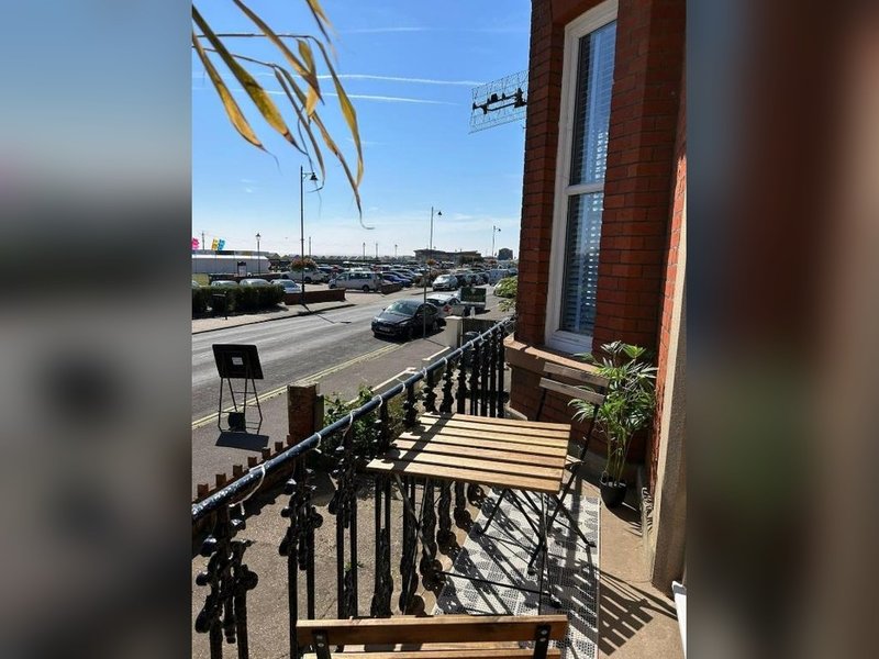 Balcony with metal railings overlooking street, parking lot and industrial area