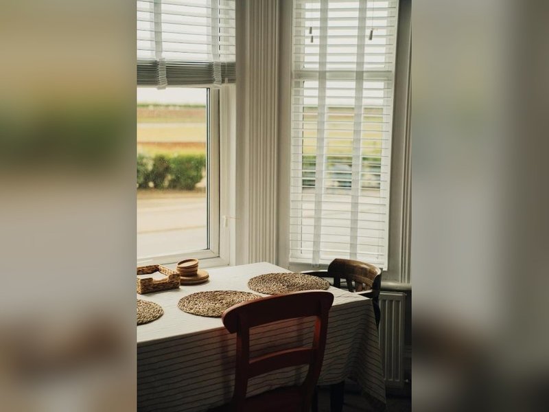 Bright window seat with wooden chair, woven baskets, and countryside view through shutters