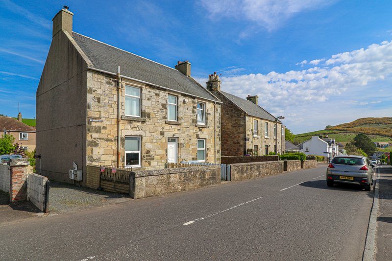 Stone-built corner house with multiple windows, slate roof and street frontage