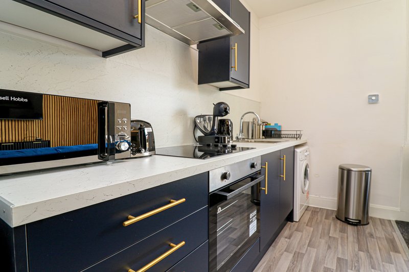 Modern kitchen with navy cabinets, white countertop, stainless steel appliances and island seating