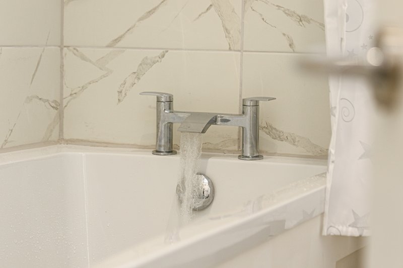 Modern bathroom with white marble-effect tiles, chrome bath faucet and white towel rail