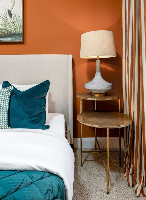 Modern bedroom with white headboard, teal velvet cushion, wood side table and table lamp