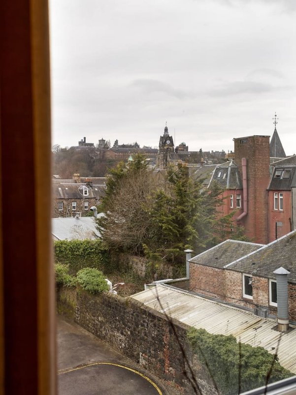 View from window of brick townhouses, garden wall, and town skyline with church spire