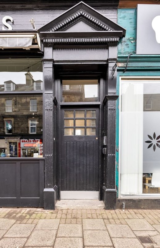Narrow black-fronted townhouse with decorative pediment and panelled door on street