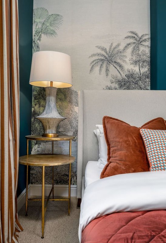 Bedroom with double bed, bedside table lamp, wall art, and terracotta cushions