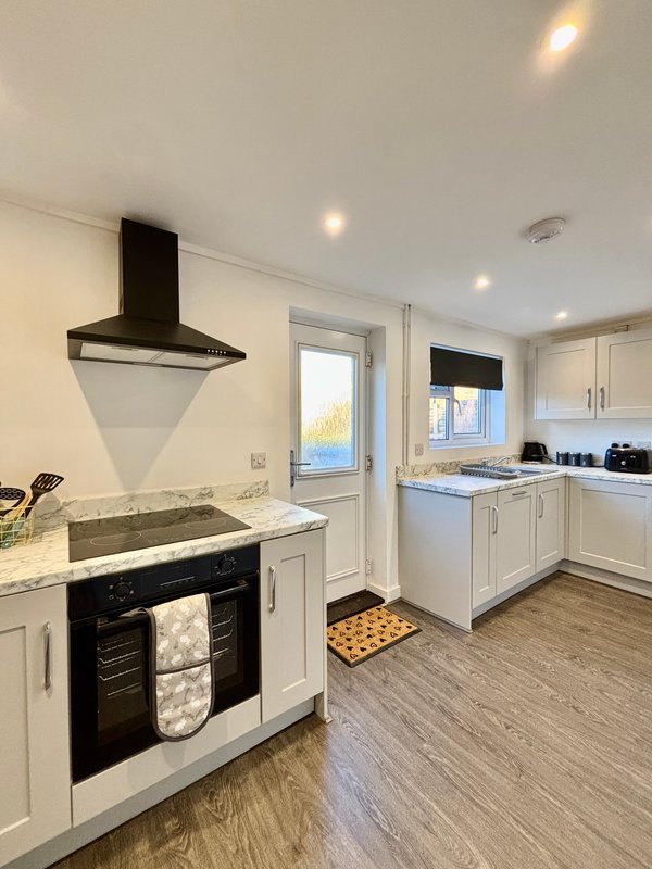 Modern kitchen with white cabinetry, black range cooker, and cream countertops