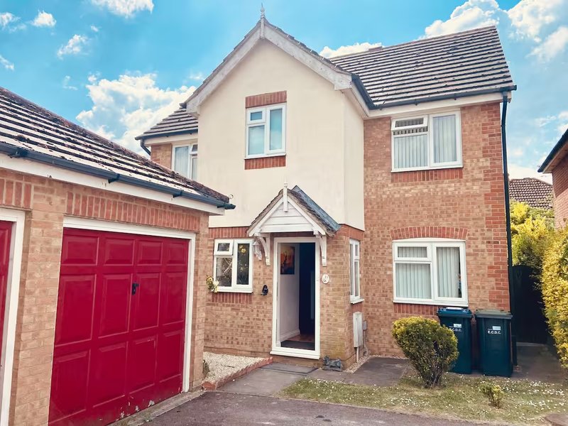 Brick detached house with red garage door, white entrance porch, and driveway