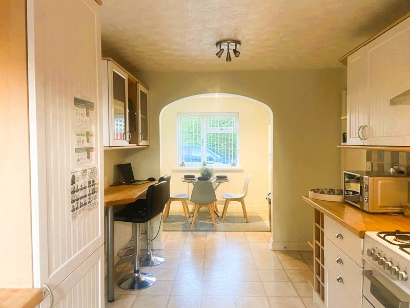 Kitchen-diner with cream cabinets, workspace area, dining table and window with garden view