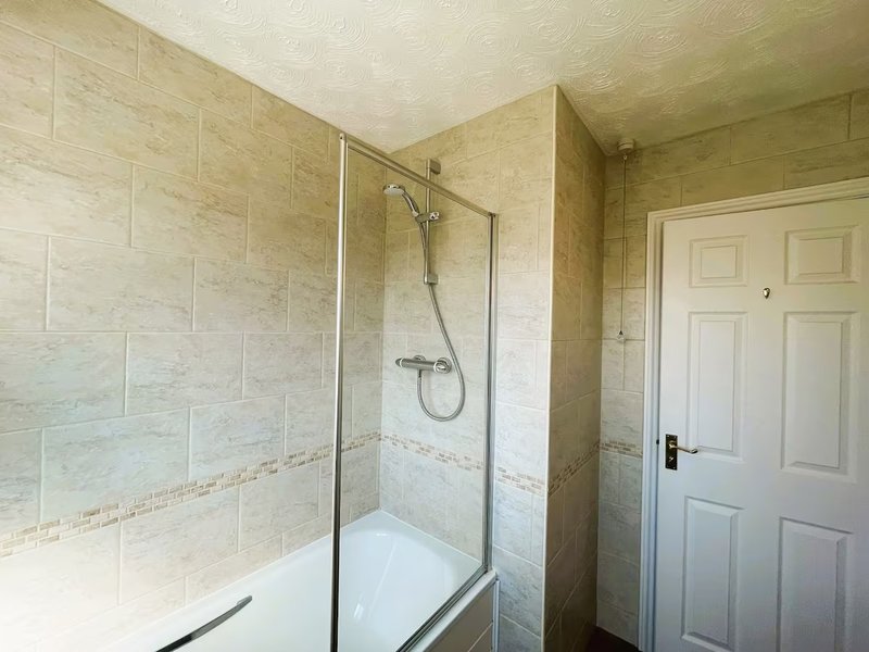 Bathroom with walk-in shower enclosure, white tile walls, and white panel door