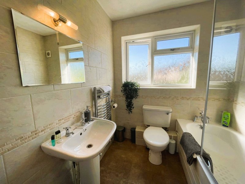 Bathroom with sink, toilet, mirror, window and shower enclosure