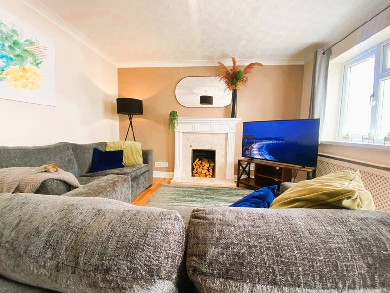 Bright living room with two gray sofas, fireplace, TV, and large windows