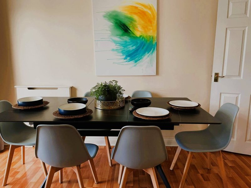 Dining room with black table, gray chairs, place settings and colorful abstract wall art