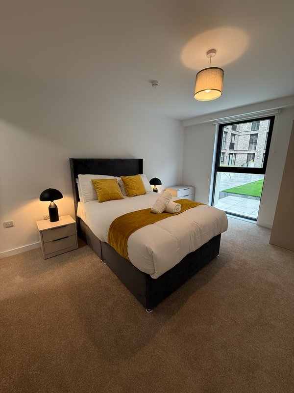 Modern bedroom with double bed, bedside lamps, and glass door to balcony