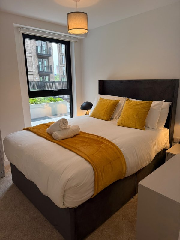 Modern bedroom with double bed, yellow accents, window overlooking city street