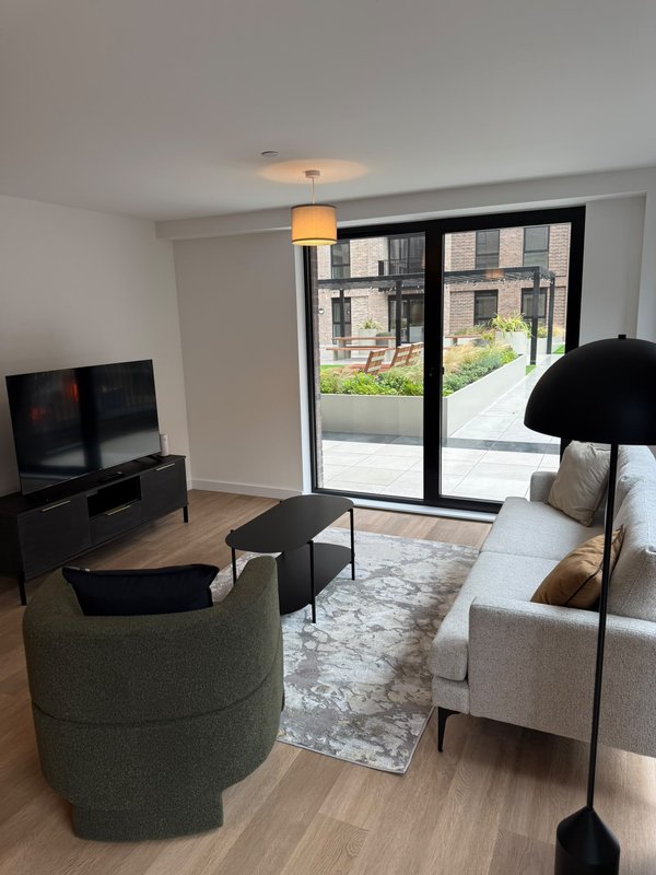 Modern living room with sofas, TV, coffee table and glass doors opening to courtyard