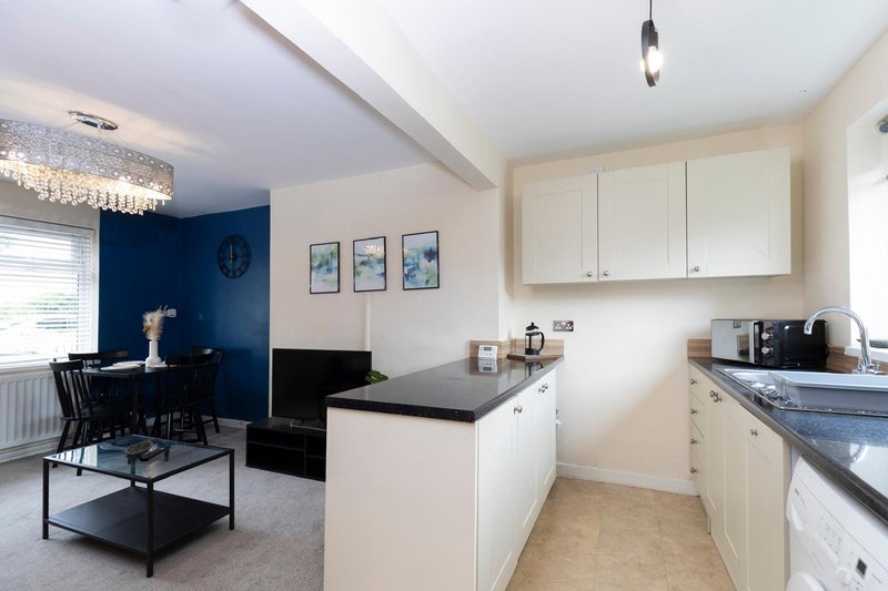 Open-plan kitchen and living area with white cabinetry, blue accent wall, and modern furnishings