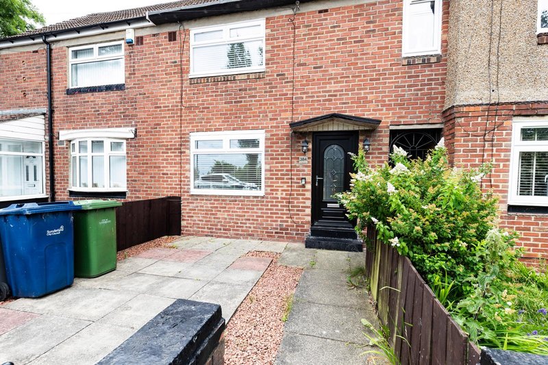 Brick terraced house exterior with paved driveway, bins, and front entrance