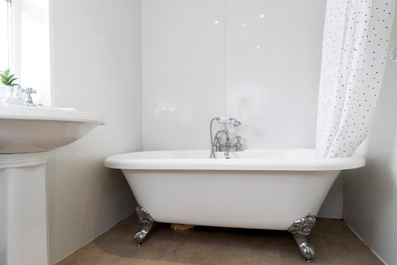 Modern bathroom with freestanding white bathtub, chrome feet, and polka-dot shower curtain