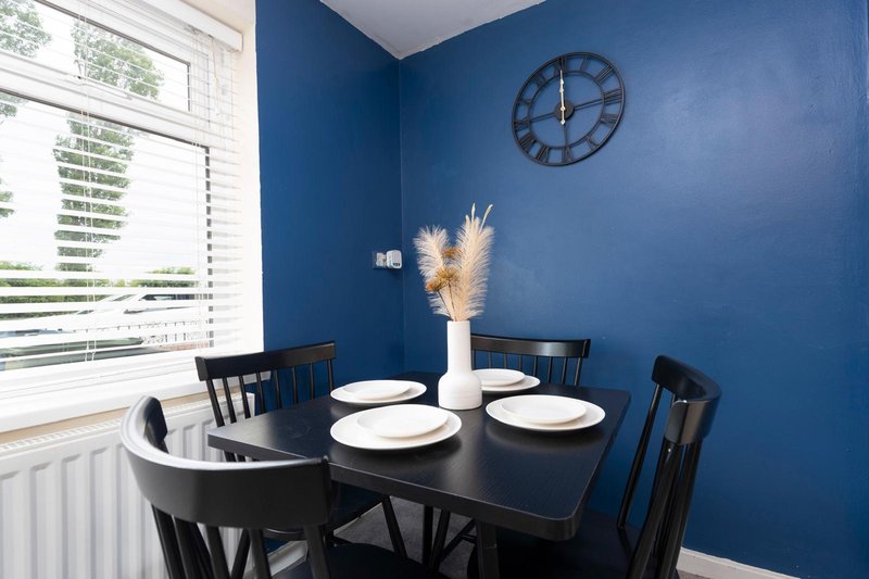 Modern dining area with black table, chairs, blue walls and wall clock