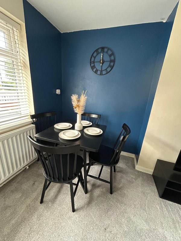 Dining nook with round black table, chairs, place settings, and blue accent wall