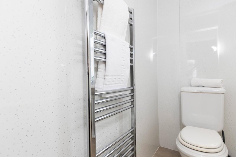 Compact bathroom with toilet, heated towel rail and white textured walls