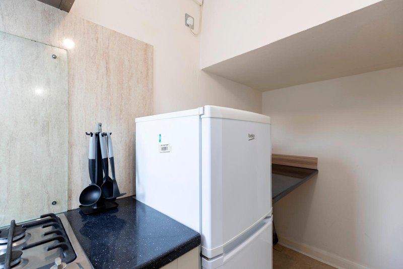Kitchen corner with white refrigerator, gas cooktop, and dark countertop