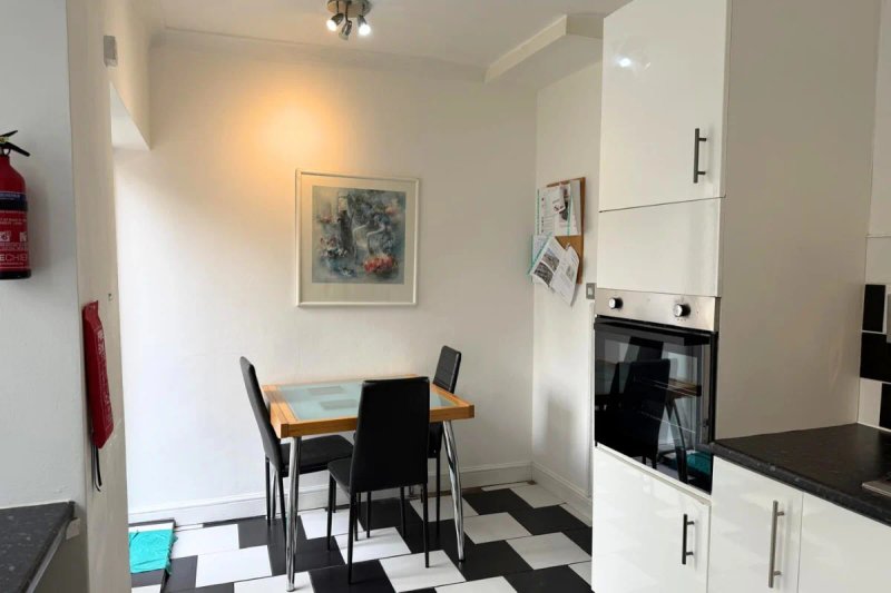 Modern kitchen with dining table, black and white chevron flooring, white cabinetry