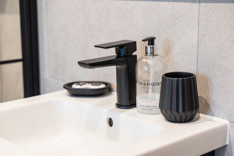 Modern bathroom sink with black tap, soap dispenser, and decorative accessories