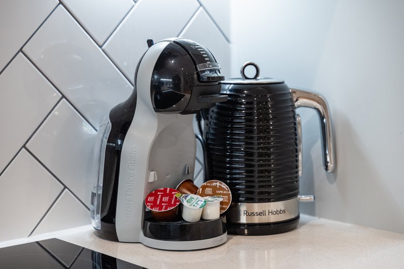 Kitchen counter with coffee maker, kettle, and small appliances against white subway tile