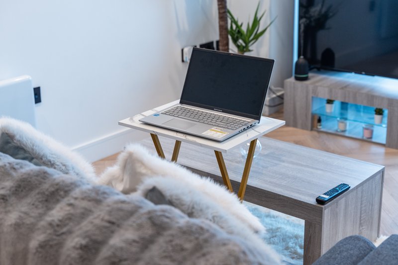 Modern workspace with laptop on desk, potted plant, and comfortable seating area