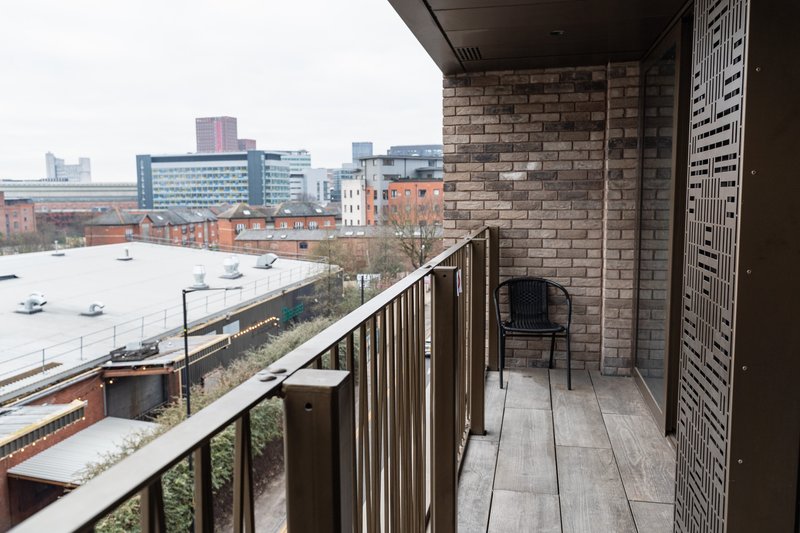 Balcony with metal railing overlooking urban waterfront, brick building exterior and city skyline