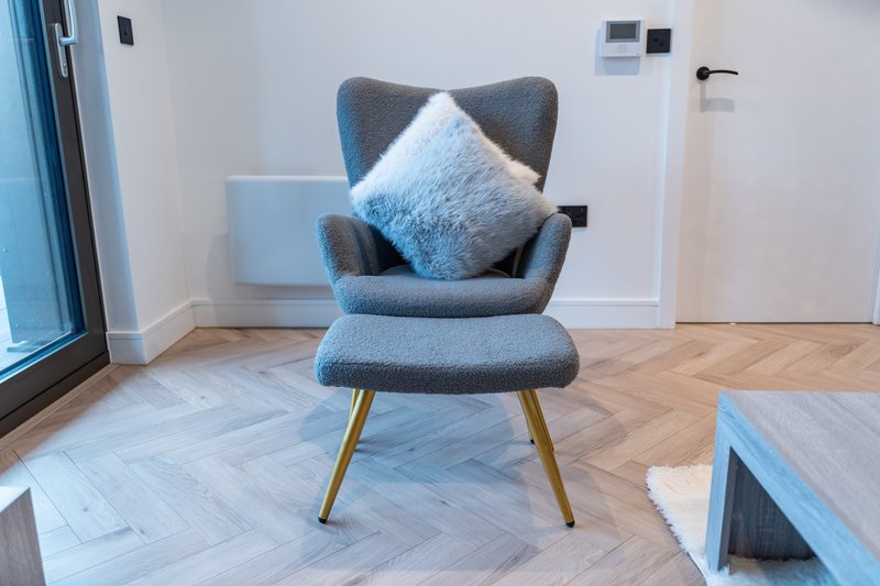 Modern blue upholstered armchair with cushion on herringbone wooden floor