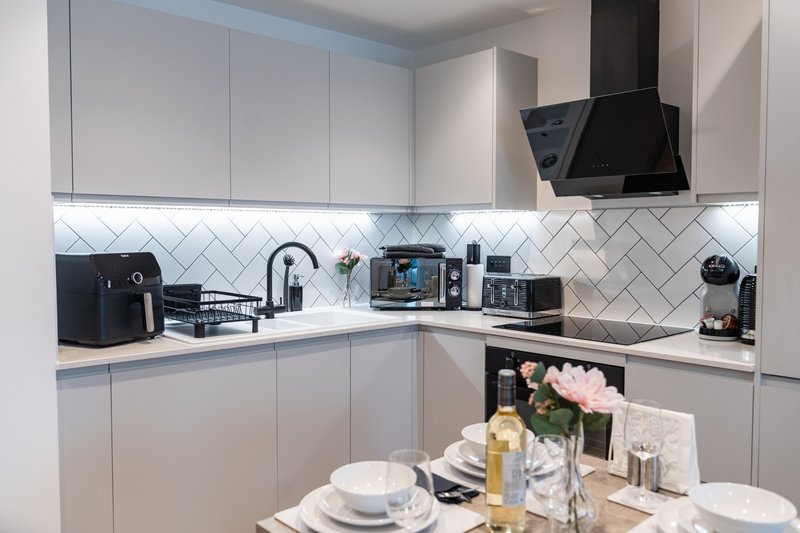 Modern kitchen with white cabinetry, herringbone backsplash, and dining table set for meal