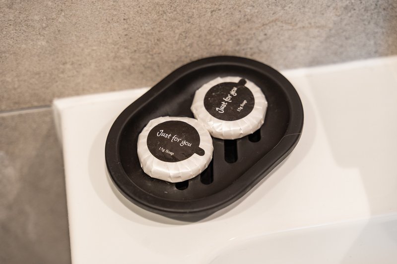Bathroom shelf with black tray holding two white soaps with text labels
