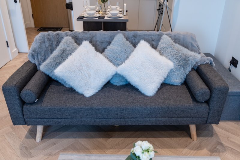 Modern grey sofa with blue and white cushions and throw blanket in bright living room