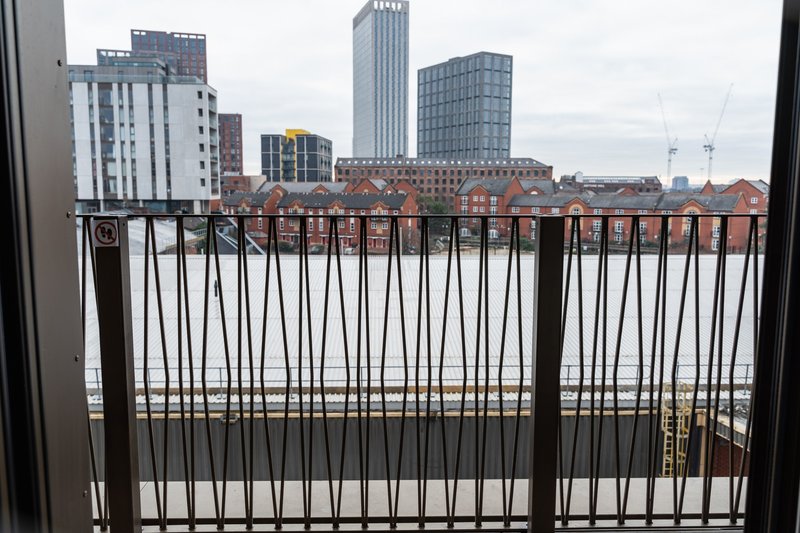 Urban cityscape view from balcony with metal railing and modern buildings