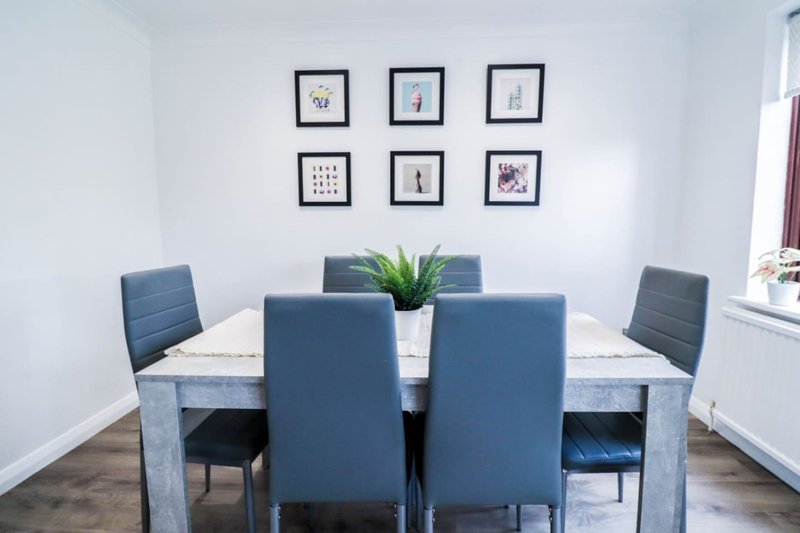 Dining room with grey table, blue chairs, framed wall art, and potted plant