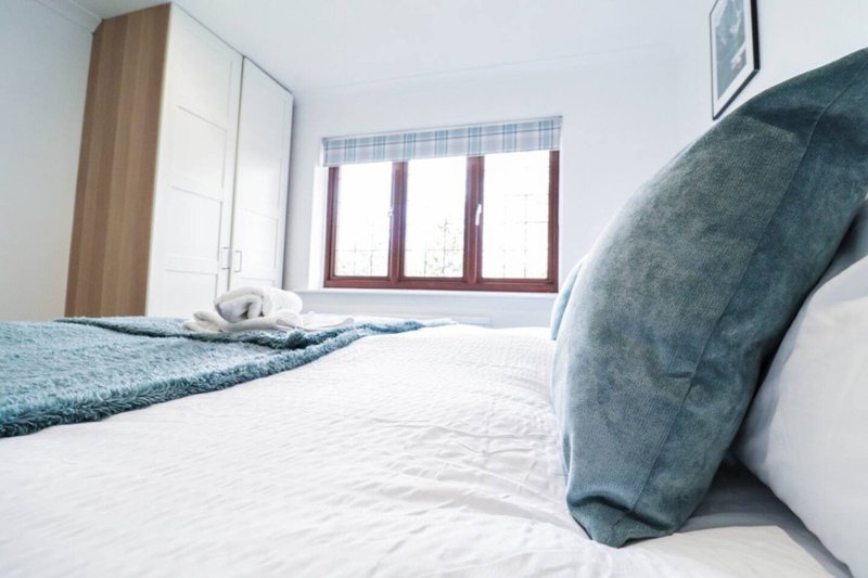 Bright bedroom with double bed, wooden wardrobe, window with shutters and blue accents
