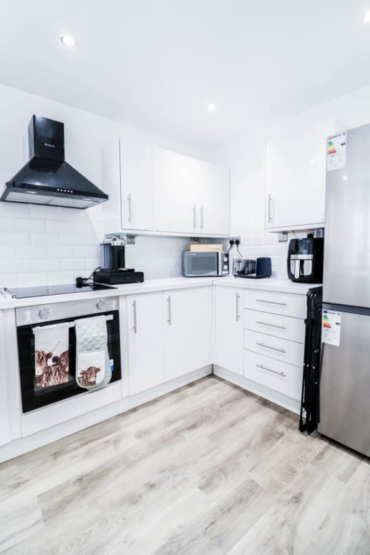 Modern white kitchen with black appliances, wooden flooring and subway tile backsplash