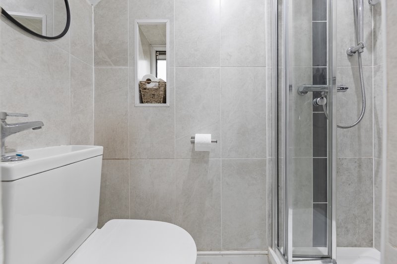 Modern bathroom with toilet, sink, shower cubicle and tiled walls