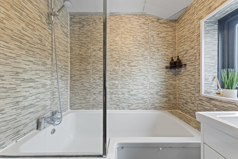 Modern bathroom with walk-in shower, bathtub, tiled walls and window
