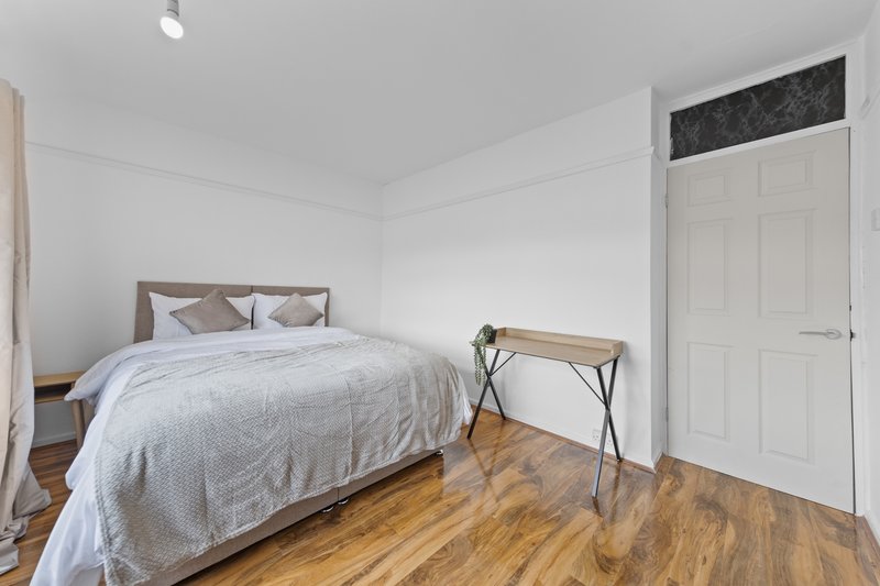 Bedroom with double bed, wooden floor, white wardrobe and small desk
