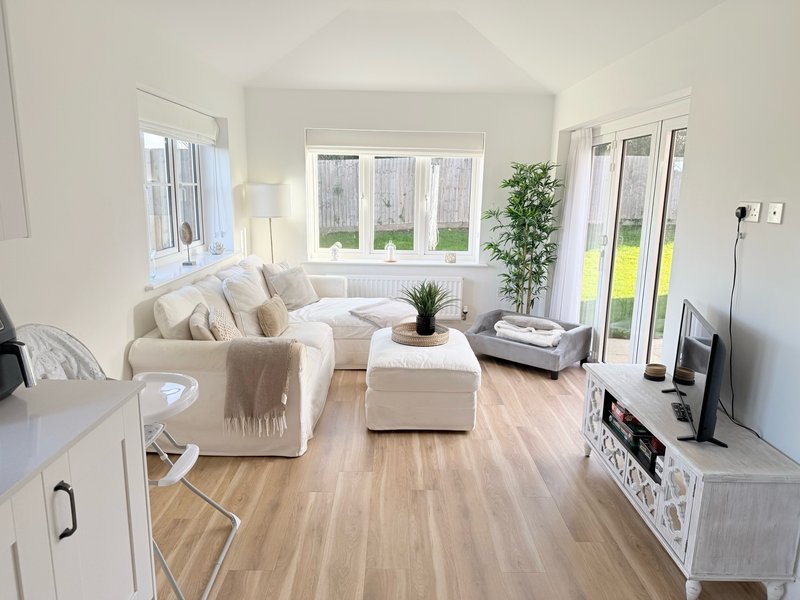 Bright open-plan living area with cream sofa, wooden flooring and patio doors to garden