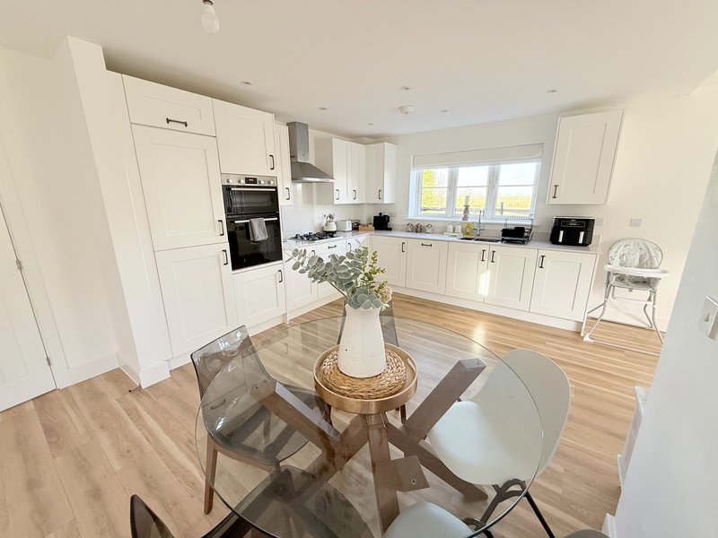 Modern kitchen and dining area with white cabinetry, wooden flooring, round table and chairs