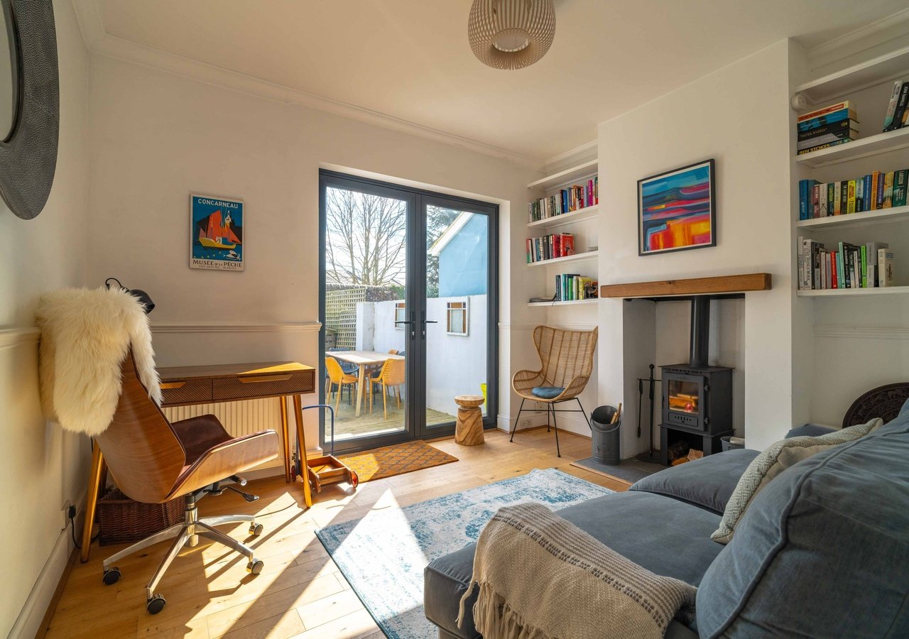 Bright bedroom with wooden chair, bookshelf, wood-burning stove and glass patio doors