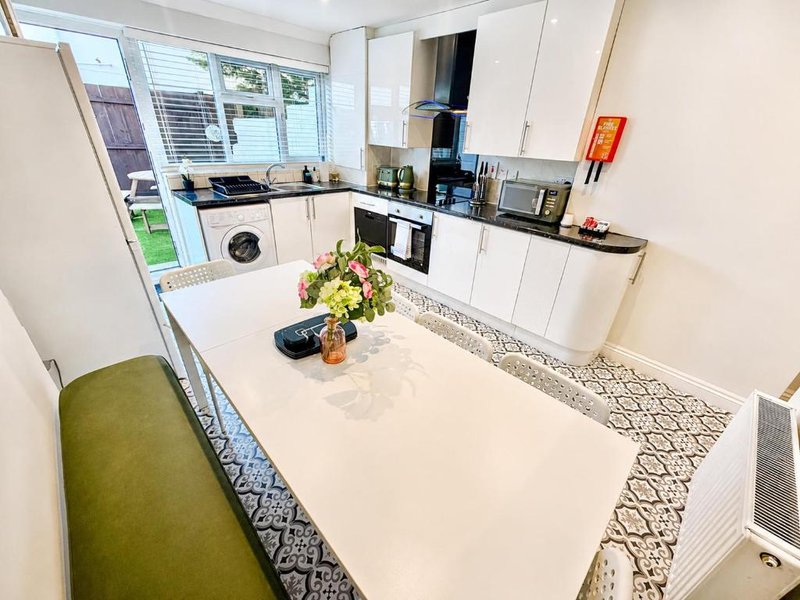 Modern kitchen with white cabinetry, island counter, built-in appliances and garden view