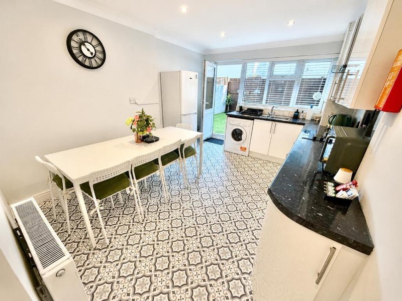 Modern kitchen and dining area with white table, cream cabinetry, black countertop and patterned flooring